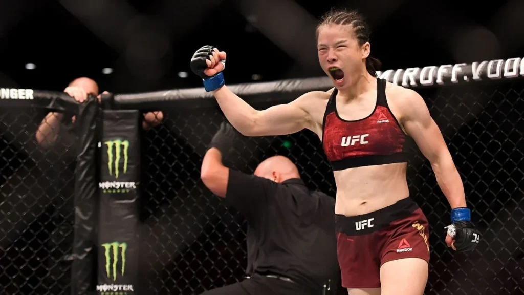 Wing Chun and MMA, Female UFC fighter  Zhang Weili in red and black gear celebrates inside the octagon, raising her fist and shouting in victory after a match.